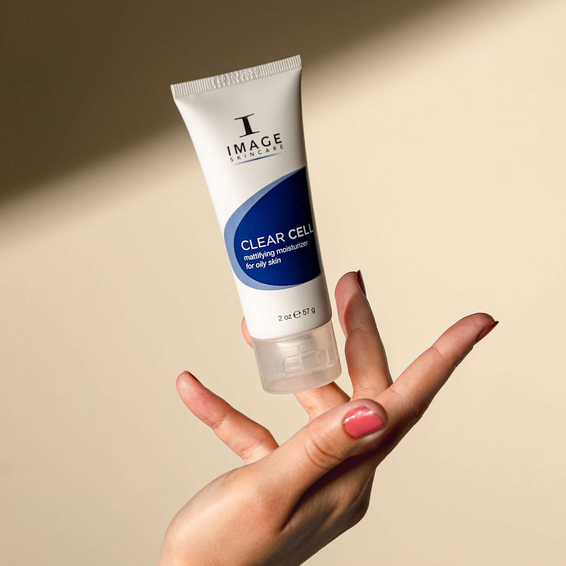 Hand holding squeeze bottle of Image Skincare CLEAR CELL Mattifying Moisturizer for Oily Skin
