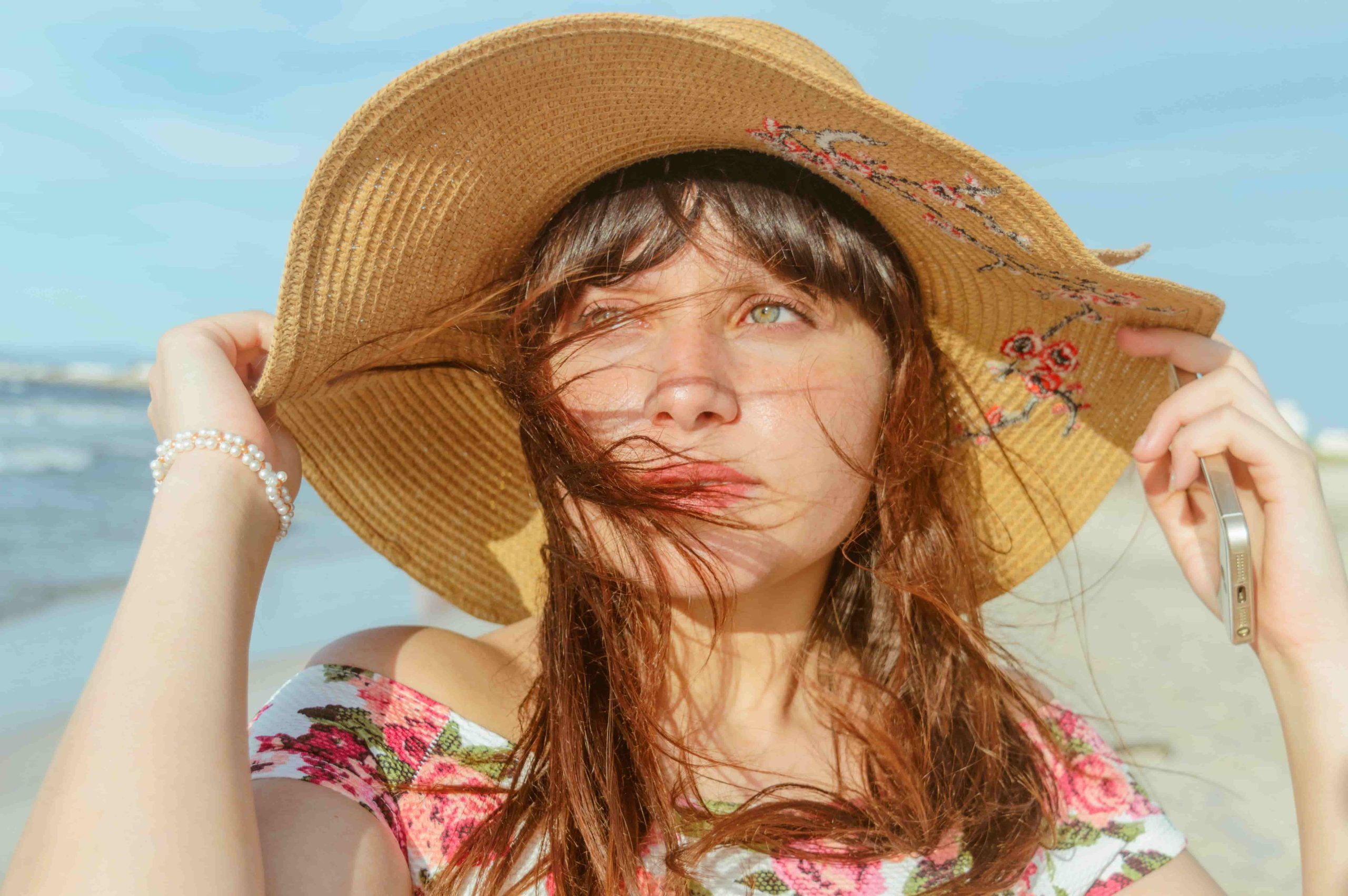 Woman wearing a sun hat outdoors in bright daylight, illustrating daily UV exposure on the skin during spring and summer